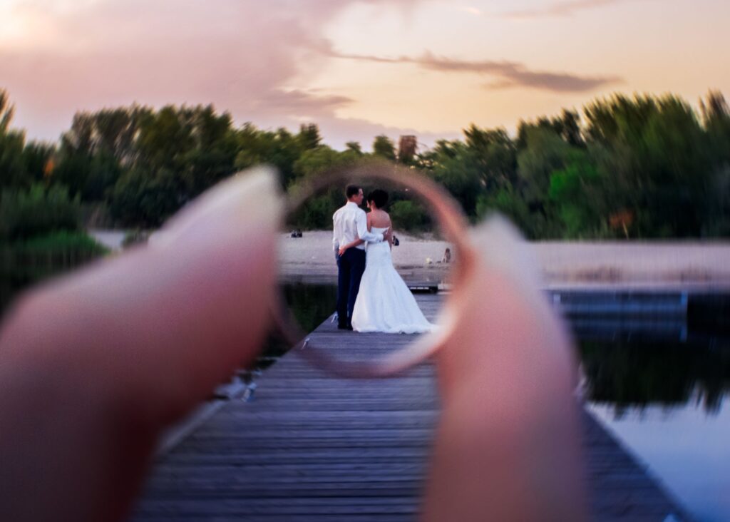 Bride and groom on a boardwalk picture taken through a ring 