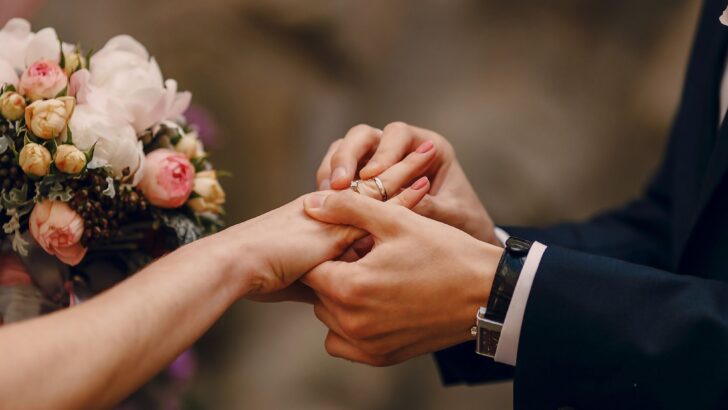 Wedding vows as the groom places a ring on brides finger 