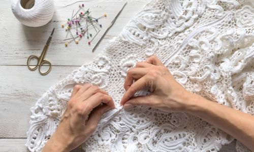 A tailor working on a lace wedding dress