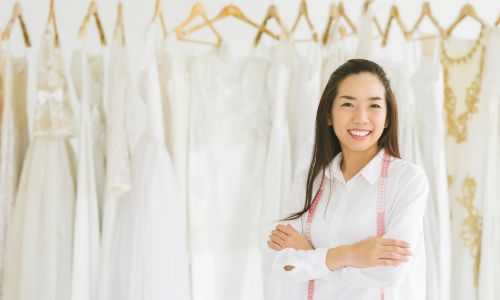 A used store owner in front of the rack with wedding dresses